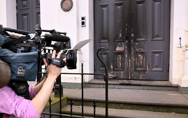 Une équipe de tournage filmant l'entrée avant incendiée de la synagogue East Melbourne, à Melbourne, le 6 juillet 2025. (Crédit : William West/AFP)