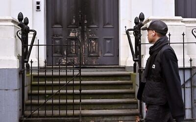 Un homme passant devant l'entrée principale incendiée de la synagogue East Melbourne, à Melbourne, le 6 juillet 2025. (Crédit : William West/AFP)
