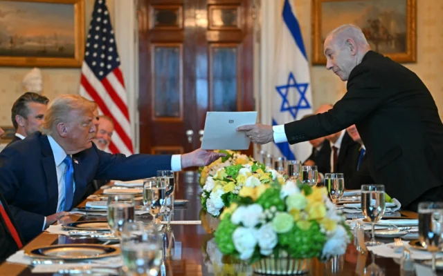 Le Premier ministre Benjamin Netanyahu remettant une lettre de recommandation au président américain Donald Trump lors de leur rencontre dans la Blue Room de la Maison Blanche, à Washington, le 7 juillet 2025. (Crédit : Andrew Caballero-Reynolds/AFP)