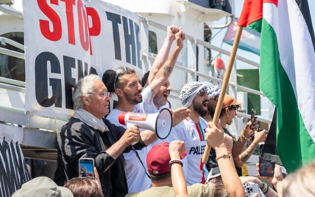 Des membres de l'équipage assistent au départ du bateau « Handala » de la flottille de la liberté pour Gaza dans un port de Syracuse, en Sicile, dans le sud de l'Italie, le 13 juillet 2025. Un bateau à destination de Gaza transportant des militants pro-palestiniens et de l'aide humanitaire a quitté la Sicile le 13 juillet 2025. (Crédit : Giovanni ISOLINO / AFP)