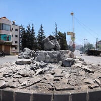 Des membres des forces de sécurité syriennes passent à moto devant un monument détruit dans la ville de Soueïda, à majorité druze, le 15 juillet 2025, à la suite d'affrontements entre des clans bédouins et des combattants druzes. (Crédit : Bakr Alkasem/AFP)
