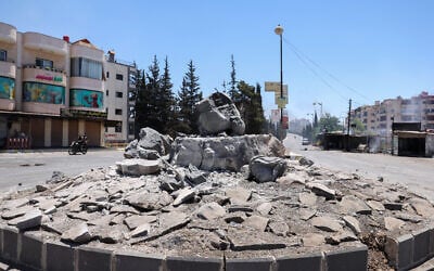 Des membres des forces de sécurité syriennes passent à moto devant un monument détruit dans la ville de Soueïda, à majorité druze, le 15 juillet 2025, à la suite d'affrontements entre des clans bédouins et des combattants druzes. (Crédit : Bakr Alkasem/AFP)