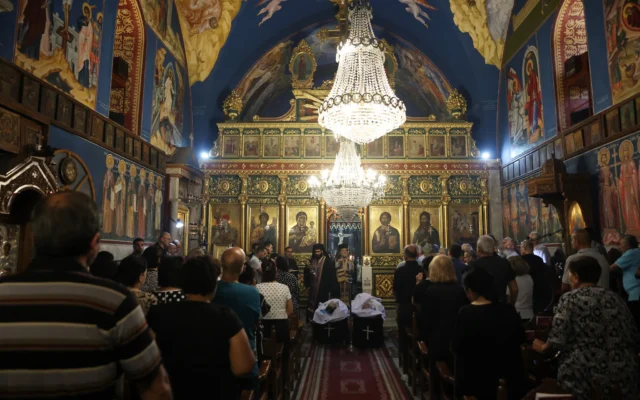 Des Palestiniens chrétiens assistent aux funérailles de Saad Salameh et Foumia Ayyad, tués lors d'une frappe israélienne sur l'église de la Sainte Famille dans la ville de Gaza. L'archevêque Alexios de l'église Saint Porphyrius dirige la messe, le 17 juillet 2025. (Crédit : Omar al-Qattaa/AFP)
