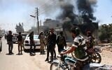 Des combattants de tribus bédouines se rassemblent près d'un bâtiment en feu dans le village d'al-Mazraa, dans le gouvernorat de Soueïda, dans le sud de la Syrie, alors que les affrontements avec des hommes armés druzes se poursuivent le 18 juillet 2025 (Crédit : Omar Haj Kadour / AFP)