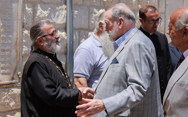 L'ambassadeur américain en Israël, Mike Huckabee (au centre), serrant la main du père Daoud Khoury, de l'Église grecque orthodoxe, lors de sa visite dans le village chrétien palestinien de Taybeh, en Cisjordanie, le 19 juillet 2025. (Crédit : Jaafar Aashtityeh/AFP)