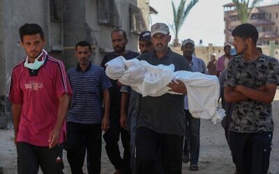 Des hommes transportent le corps enveloppé dans un linceul du jeune Palestinien Abdul Jawad al-Ghalban, 14 ans, apparemment mort de faim, avant son enterrement à l’hôpital Nasser de Khan Younès, dans le sud de la bande de Gaza, le 22 juillet 2025. (Crédit : AFP)