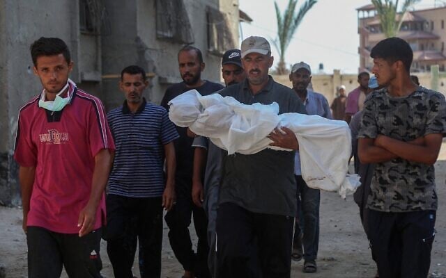 Des hommes transportent le corps enveloppé dans un linceul du jeune Palestinien Abdul Jawad al-Ghalban, 14 ans, apparemment mort de faim, avant son enterrement à l’hôpital Nasser de Khan Younès, dans le sud de la bande de Gaza, le 22 juillet 2025. (Crédit : AFP)