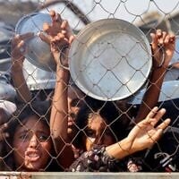 Des Palestiniens, principalement des enfants, poussent pour recevoir un repas chaud dans une cuisine de charité dans le quartier de Mawasi à Khan Younis dans le sud de la bande de Gaza le 22 juillet 2025. (Crédit : AFP)