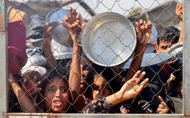 Des Gazaouis, principalement des enfants, se bousculant pour recevoir un repas chaud dans une cuisine communautaire du quartier d'al-Mawasi, à Khan Younès, dans le sud de la bande de Gaza, le 22 juillet 2025. (Crédit : AFP) Des Gazaouis, principalement des enfants, se bousculant pour recevoir un repas chaud dans une cuisine communautaire du quartier d'al-Mawasi, à Khan Younès, dans le sud de la bande de Gaza, le 22 juillet 2025. (Crédit : AFP)