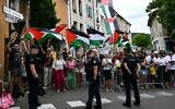 Des gendarmes français formant un périmètre tandis que des spectateurs brandissent des drapeaux "palestiniens" le long du parcours de la 17ᵉ étape de la 112ᵉ édition du Tour de France, entre Bollène et Valence, dans le sud de la France, le 23 juillet 2025. (Crédit : Loic Venance/AFP)