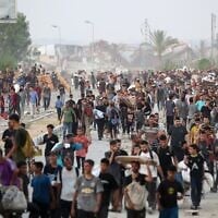 Des Gazaouis marchant dans la rue al-Rashid, dans l'ouest de Jabaliya, le 23 juillet 2025, après avoir reçu de l'aide humanitaire dans un centre de distribution situé dans le nord de la bande de Gaza. (Crédit : Eyad Baba/AFP)