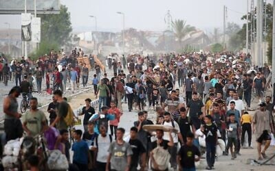 Des Gazaouis marchant dans la rue al-Rashid, dans l'ouest de Jabaliya, le 23 juillet 2025, après avoir reçu de l'aide humanitaire dans un centre de distribution situé dans le nord de la bande de Gaza. (Crédit : Eyad Baba/AFP)