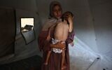 Hidaya, une mère palestinienne de 31 ans, berce son fils Mohammed al-Mutawaq, âgé de 18 mois et malade, qui présente également des signes de malnutrition, dans leur tente du camp de réfugiés d'Al-Shati, à l'ouest de Gaza-City, le 24 juillet 2025. (Crédit : Omar AL-QATTAA / AFP)
