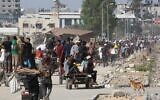 Des Gazaouis déplacés dans le camp de réfugiés de Nuseirat transportant des colis alimentaires et d'autres articles qu'ils ont réussi à obtenir auprès d'un point de distribution de l'aide de la GHF, dans le centre de la bande de Gaza, le 30 juillet 2025. (Crédit : Eyad Baba/AFP)
