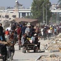 Des Gazaouis déplacés dans le camp de réfugiés de Nuseirat transportant des colis alimentaires et d'autres articles qu'ils ont réussi à obtenir auprès d'un point de distribution de l'aide de la GHF, dans le centre de la bande de Gaza, le 30 juillet 2025. (Crédit : Eyad Baba/AFP)