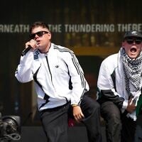 Naoise Ó Cairealláin (à gauche) et Liam Óg, du trio de hip-hop Kneecap, sur scène lors du festival de Glastonbury, le 28 juin 2025. (Crédit : Scott A Garfitt/Invision/AP)