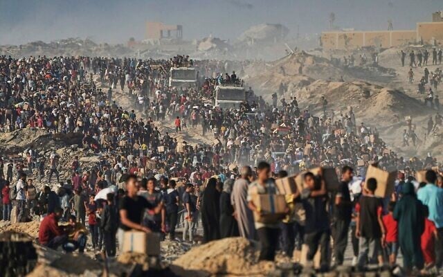 Des Palestiniens transportent des sacs et des caisses de nourriture et d'aide humanitaire, déchargés d'un convoi du Programme alimentaire mondial se dirigeant vers la ville de Gaza, dans le nord de la bande de Gaza, le 16 juin 2025. (Crédit : AP Photo/Jehad Alshrafi)