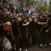 Des personnes aux funérailles des Américains d'origine palestinienne Saif Musallet, 20 ans, et Mohammed al-Shalabi lors de leurs funérailles dans le village d'Al-Mazraa ash-Sharqiya en Cisjordanie, le dimanche 13 juillet 2025. (Crédit : Leo Correa/AP)