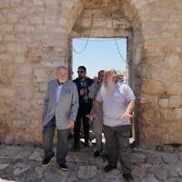 L'Ambassadeur des États-Unis en Israël Mike Huckabee, à gauche, est escorté par le Père Jack-Noble Abed, prêtre de l'Église grecque-catholique melchite, lors d'une visite du site archéologique de l'Église Saint-Georges, site d'une récente attaque de résidents d'implantations, lors de sa visite dans la ville de Taybeh, à l'est de Ramallah, en Cisjordanie, le 19 juillet 2025. (Crédit : Nasser Nasser/AP)