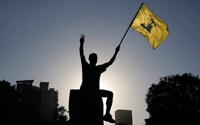 Un partisan du Hezbollah brandit un drapeau du Hezbollah devant le siège de la Commission économique et sociale des Nations Unies pour l'Asie occidentale (CESAO) à Beyrouth, au Liban, le 26 juillet 2025. (Crédit : AP Photo/Bilal Hussein)