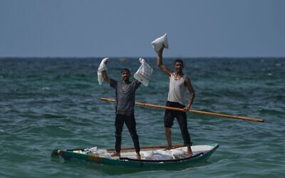 Des Palestiniens collectent de l'aide qui a atterri dans la mer Méditerranée après avoir été larguée au-dessus du centre de Gaza, sur le rivage de Zawaida, dans la bande de Gaza, le 29 juillet 2025. (Crédit : AP Photo/Abdel Kareem Hana)