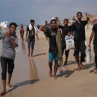Des Gazaouis récupèrent de l’aide humanitaire, larguée au-dessus du territoire et échouée sur la côte de Zawaida, dans le centre de la bande de Gaza, le 29 juillet 2025. (Crédit : Abdel Kareem Hana/AP)