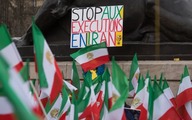 Un manifestant brandit une pancarte sur laquelle on peut lire « Stop aux exécutions en Iran » alors que des manifestants de l'opposition iranienne portent leurs drapeaux nationaux à Paris lors d'un rassemblement pour protester contre la visite du président iranien, Hassan Rouhani, en France, le 28 janvier 2016. (Crédit : AP Photo/Zacharie Scheurer)