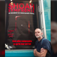 Christopher Joseph devant l’affiche de son film, « Shoah Symphonie ». (Crédit : Christopher Joseph)