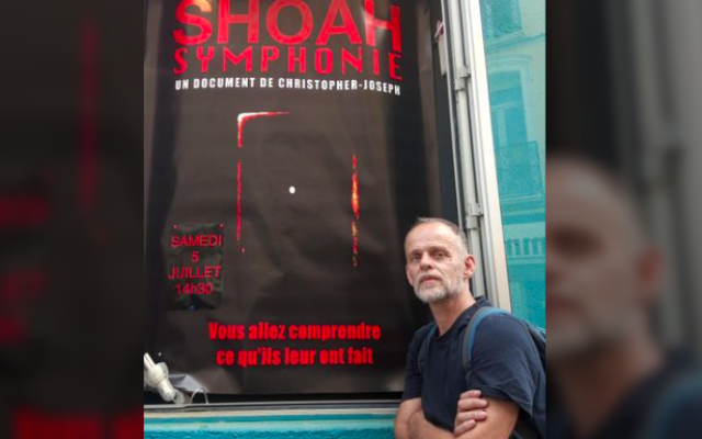 Christopher Joseph devant l’affiche de son film, « Shoah Symphonie ». (Crédit : Christopher Joseph)