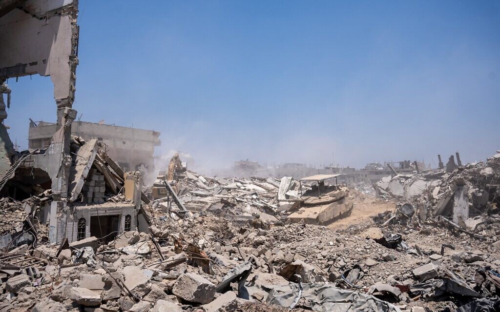 Une excavatrice de l'armée israélienne, sécurisée par un char, détruisant un bâtiment à la périphérie des quartiers de Daraj et Tuffah, à Gaza-City, le 23 juillet 2025. (Crédit : Emanuel Fabian/Times of Israel)