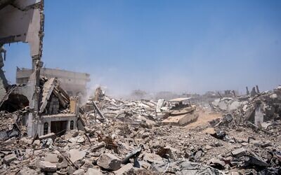 Une excavatrice de l'armée israélienne, sécurisée par un char, détruisant un bâtiment à la périphérie des quartiers de Daraj et Tuffah, à Gaza-City, le 23 juillet 2025. (Crédit : Emanuel Fabian/Times of Israel)