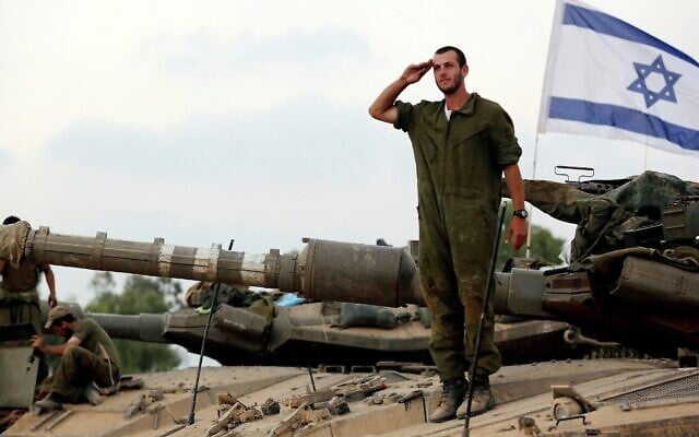 Image d'illustration : un soldat israélien sur un char salue devant un drapeau israélien à un point de rassemblement de Tsahal dans un champ, près de la frontière israélienne avec Gaza, 2014. (Crédit : Edi Israel/FLASH90)