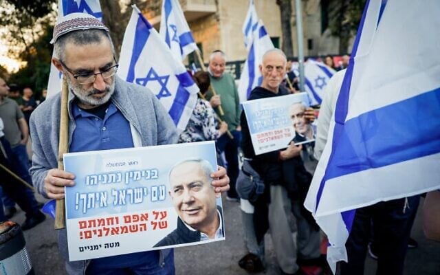 Un Israélien de droite participe à un rassemblement en faveur du plan de réforme judiciaire prévu par le gouvernement, devant la Maison du Président à Jérusalem, le 3 avril 2023. Sur sa pancarte, on peut lire : "Benjamin Netanyahu, le peuple d'Israël est avec vous, malgré l'opposition des gauchistes". (Crédit : Erik Marmor/Flash90) Un Israélien de droite participe à un rassemblement en faveur du plan de réforme judiciaire prévu par le gouvernement, devant la Maison du Président à Jérusalem, le 3 avril 2023. Sur sa pancarte, on peut lire : "Benjamin Netanyahu, le peuple d'Israël est avec vous, malgré l'opposition des gauchistes". (Crédit : Erik Marmor/Flash90)