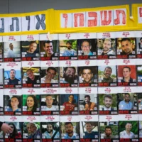 Des gens marchent à côté de photos d'otages détenus par des terroristes à Gaza, à Jérusalem, le 2 juillet 2025 (Crédit : Yonatan Sindel/Flash90)