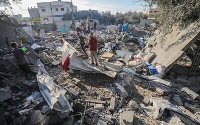 Des Gazaouis sur le site d'une frappe aérienne israélienne, dans le camp de réfugiés d'al-Shati, dans le centre de la bande de Gaza, le 13 juillet 2025. (Crédit : Ali Hassan/Flash90)
