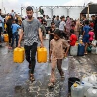 Des Gazaouis collectant de l'eau potable, à Khan Younès, dans le sud de la bande de Gaza, le 13 juillet 2025. (Crédit : Abed Rahim Khatib/Flash90)