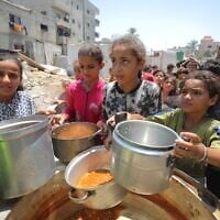 Des Palestiniens reçoivent des repas de bénévoles à  Gaza City, le 28 juillet 2025. (Crédit : Ali Hassan/Flash90)