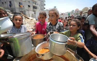 Des Palestiniens reçoivent des repas de bénévoles à  Gaza City, le 28 juillet 2025. (Crédit : Ali Hassan/Flash90)