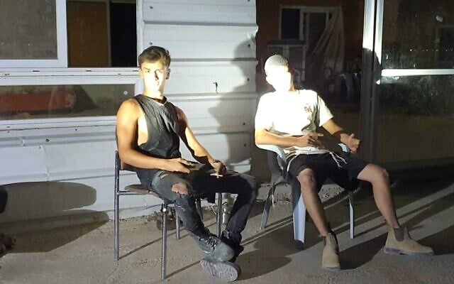 Deux Israéliens assis devant la maison d'une famille palestinienne dans le village de Muarajat al-Sharqiya, en Cisjordanie, après avoir fait irruption chez eux et forcé la famille à fuir, le 3 juillet 2025. (Crédit : Looking the Occupation in the Eye) Deux Israéliens assis devant la maison d'une famille palestinienne dans le village de Muarajat al-Sharqiya, en Cisjordanie, après avoir fait irruption chez eux et forcé la famille à fuir, le 3 juillet 2025. (Crédit : Looking the Occupation in the Eye)