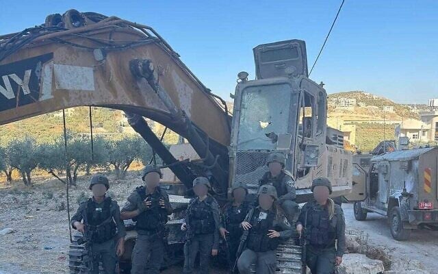 Des gardes-frontières posant avec une excavatrice soupçonnée d'avoir été volée à l'armée, sur une photo diffusée le 17 juillet 2025. (Crédit : Porte-parole de la police)