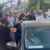 Un policier escortant la voiture du député Ayman Odeh, encerclée par des manifestants d'extrême droite, à Ness Ziona, le 19 juillet 2025. (Crédit : Capture d'écran/X ; utilisée conformément à l'article 27a de la loi sur le droit d'auteur)