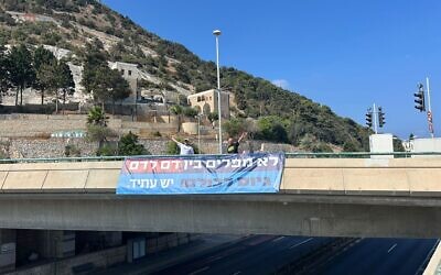 Une banderole sur laquelle on peut lire « Pas de discrimination entre le sang et le sang. Recrutement pour tous » accrochée sur un pont, en Israël, le 16 juillet 2025. (Crédit : Autorisation)