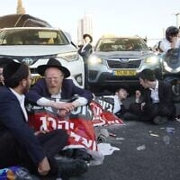 Des manifestants haredim protestant contre les efforts visant à enrôler les étudiants en yeshiva dans l'armée israélienne à l'entrée de Jérusalem, le 23 juillet 2025. (Crédit : Charlie Summers/Times of Israel)