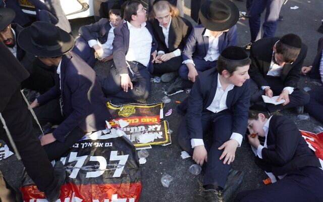 Des manifestants haredim protestant contre les efforts visant à enrôler les étudiants en yeshiva dans l'armée israélienne, à l'entrée de Jérusalem, le 23 juillet 2025. (Crédit : Charlie Summers/Times of Israel)