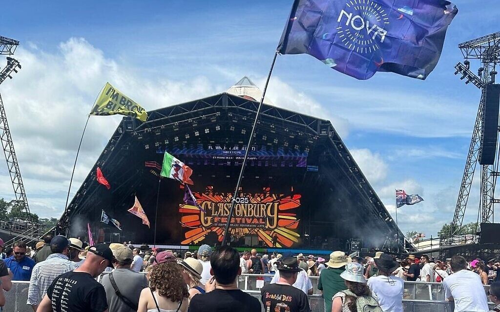 Michael Garcia brandit un drapeau du festival Supernova, en hommage aux victimes du 7 octobre 2023, lors du festival de Glastonbury, au Royaume-Uni, en juin 2025. (Crédit : Autorisation)