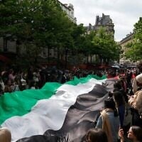 Des étudiants brandissant un drapeau "palestinien" géant lors d'un rassemblement en faveur des Palestiniens et contre Israël, à l'université de la Sorbonne, à Paris, le 29 avril 2024. (Crédit : Geoffroy Van Der Hasselt/AFP)