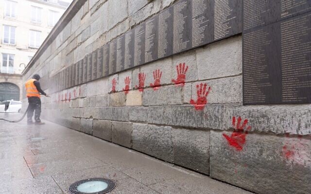 Un employé municipal nettoie le « Mur des Justes » au mémorial de la Shoah, à Paris, vandalisé, le 14 mai 2024. (Crédit : Antonin Utz/AFP) Un employé municipal nettoie le « Mur des Justes » au mémorial de la Shoah, à Paris, vandalisé, le 14 mai 2024. (Crédit : Antonin Utz/AFP)