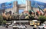 Des véhicules passent devant une bannière anti-Israël représentant des soldats iraniens en train de converger vers le territoire israélien sur la place Enghelab (Révolution), à Téhéran, le 24 juin 2025 (ATTA KENARE / AFP)
