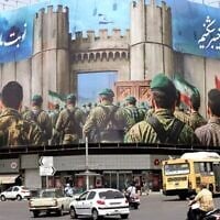 Des véhicules passent devant une bannière anti-Israël représentant des soldats iraniens en train de converger vers le territoire israélien sur la place Enghelab (Révolution), à Téhéran, le 24 juin 2025 (ATTA KENARE / AFP)