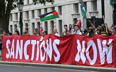 Des manifestants brandissent une banderole appelant à l'imposition de sanctions à Israël lors d'une manifestation de soutien aux Palestiniens de Gaza dans un contexte de craintes de famine dans le territoire en proie à la guerre, devant Downing Street, à Londres, le 29 juillet 2025. (JUSTIN TALLIS / AFP)